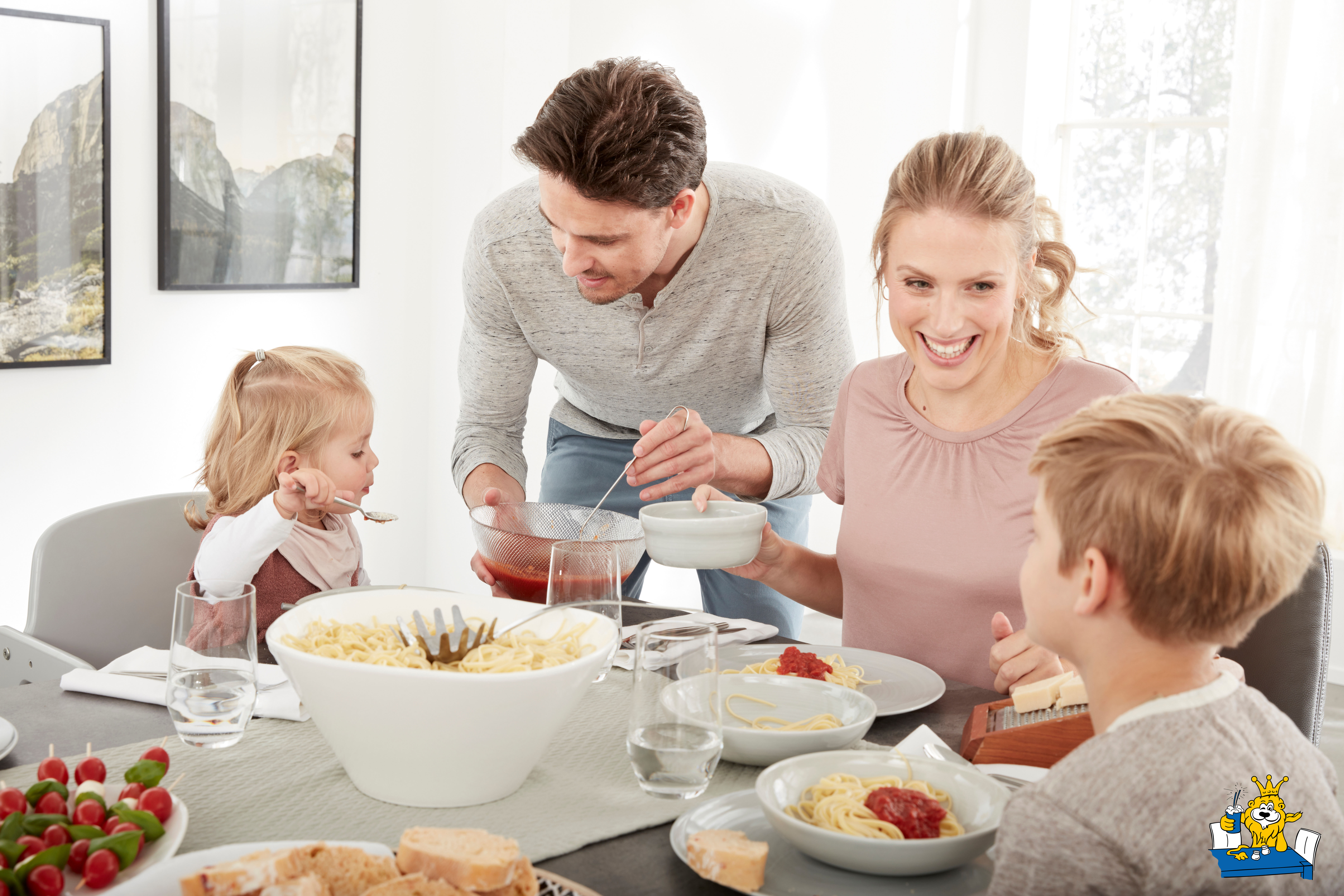 Eine Familie die am Esstisch sitzt und Spaghetti´s essen.
