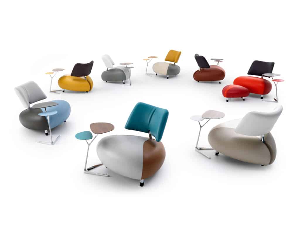 Eine Sammlung moderner, einzigartig gestalteter Stühle, die in einem Kreis angeordnet sind. Jeder Stuhl hat eine individuelle Farbkombination und verfügt über einen kleinen, integrierten Tisch. Die ergonomisch geformten Sitzmöbel kombinieren Leder und Stoff und vereinen zeitgenössisches Design mit funktionaler Arbeitsfläche