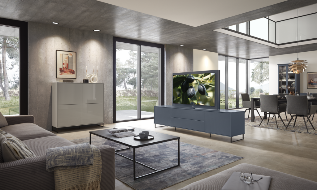 Wohnzimmer mit modernen Möbeln in Olivgrau und Nussbaum-Furnier, inklusive Vitrine, Lowboard und TV-Board – stilvoll, aufgeräumt und lichtdurchflutet.