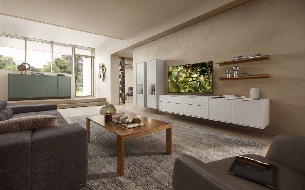 Modernes Wohnzimmer mit grauem Ecksofa, weißem TV-Board, Holz-Couchtisch und offenem Regal – lichtdurchflutet, aufgeräumt und stilvoll eingerichtet.