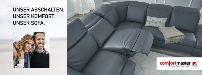 Modernes Wohnzimmer mit großem, grauem Ecksofa in Relaxfunktion. Das Sofa ist mit einem gemusterten Kissen und einer beigen Decke dekoriert. Der Raum ist in Grau- und Naturtönen gehalten, mit hellem Boden und stilvollen Wandpaneelen. Links oben im Bild steht in großen Buchstaben: ‚UNSER ABSCHALTEN. UNSER KOMFORT. UNSER SOFA.‘ Unten rechts befindet sich das ‚comfortmaster‘ Logo mit dem Claim: ‚besser sitzen, liegen, leben.‘ – ein ausdrucksstarkes Kampagnenmotiv, das Komfort und Entspannung ins Zentrum stellt.