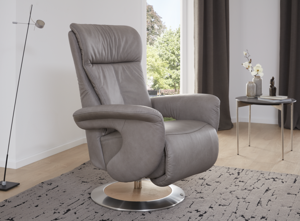 Moderner Relaxsessel aus grauem Leder mit Metallgestell in stilvollem Wohnzimmerambiente – platziert auf einem strukturierten Teppich mit Beistelltisch, dekorativen Vasen und großem Fenster mit Blick ins Grüne.