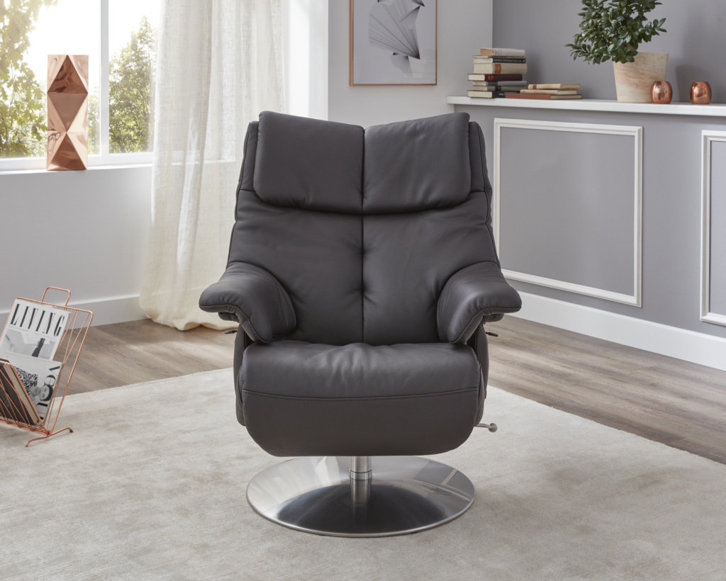 Schwarzer Leder-Relaxsessel mit gepolsterten Armlehnen und Metall-Drehfuß in modernem Wohnzimmer mit hellem Teppich, Holzfußboden und dekorativer Wandverkleidung – ergänzt durch Kupfer-Accessoires und Bücherregal mit Pflanzen