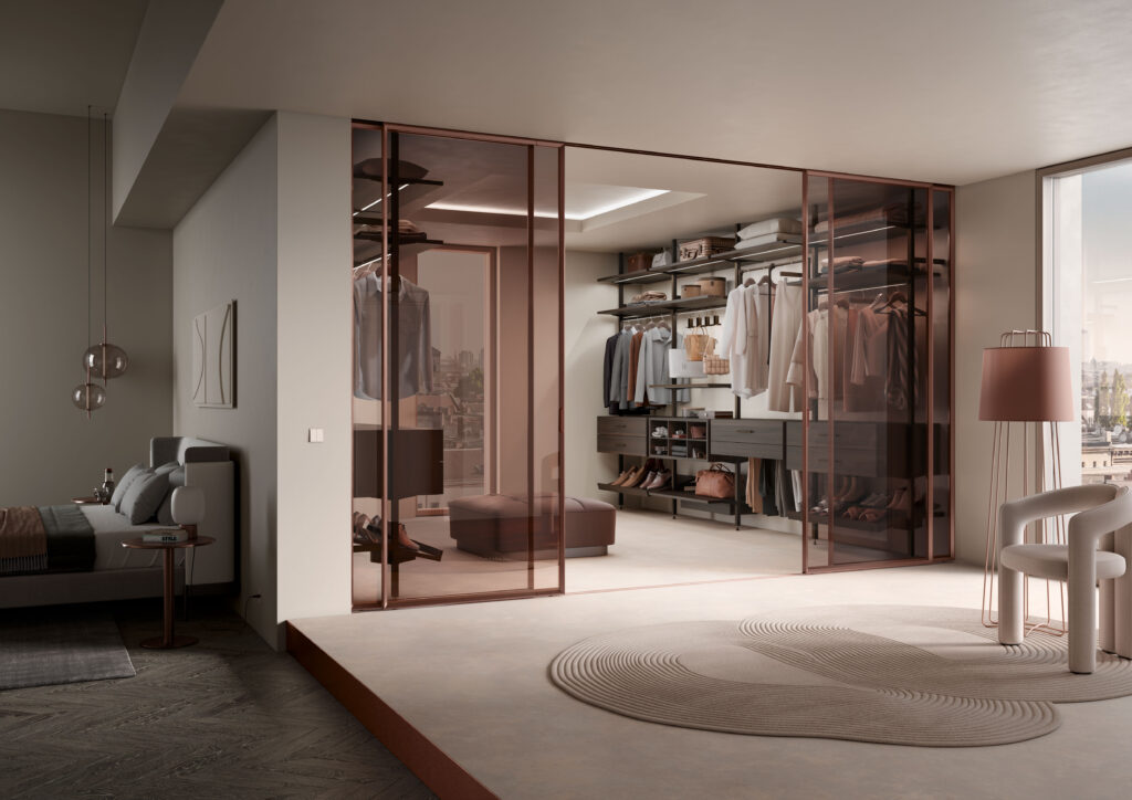 Begehbarer Kleiderschrank mit Gleittür Facet, Glasfronten, Innensystem Legno, beleuchteten Fachböden und Schubkästen – angrenzendes Schlafzimmer im modernen Design