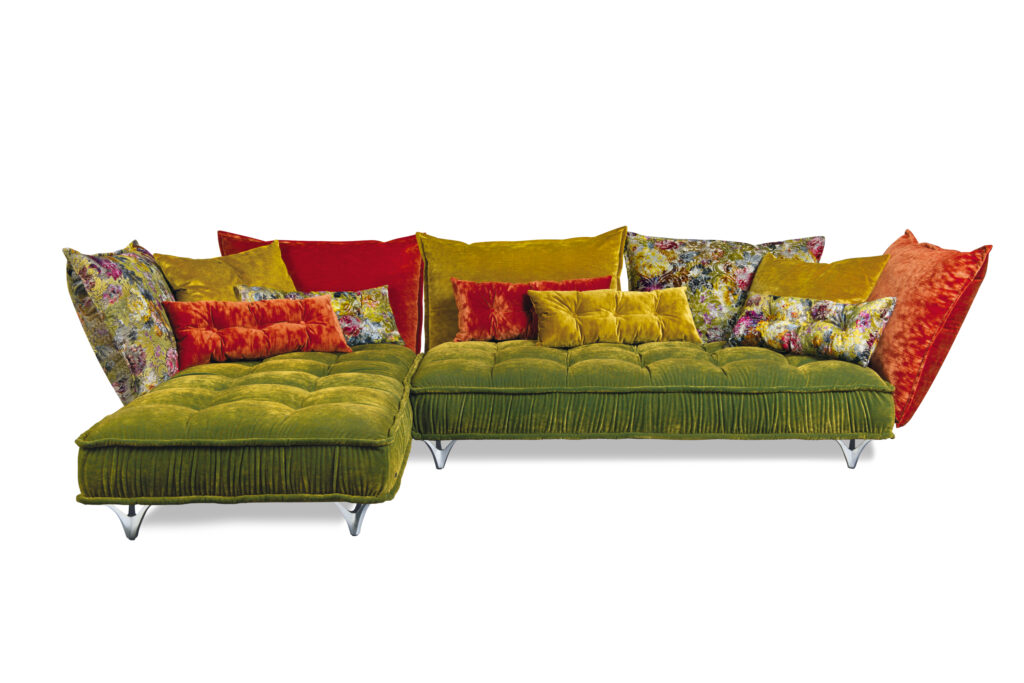Ohlinda-Sofa von Bretz in lebendigem Grün mit floralen und farbenfrohen Kissen – extravagantes Design mit schwebenden Rückenlehnen, Lilienfüßen und detailreicher Polsterung.