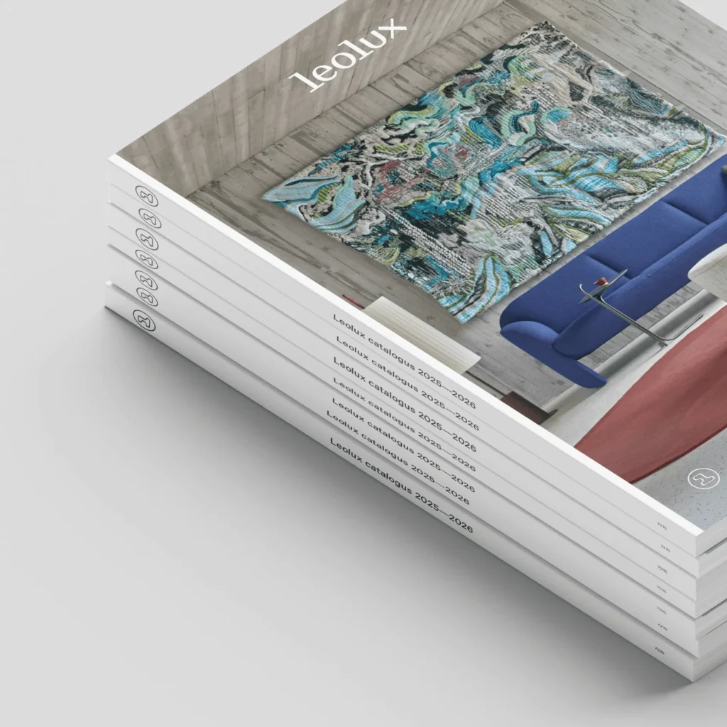 Stapel von fünf Leolux-Katalogen 2023–2024 mit Titelansicht – moderne Covergestaltung mit blauem Sofa, rotem Teppich und abstrakter Wandkunst, sichtbar gebrandet mit Leolux-Logo auf dem oberen Exemplar.