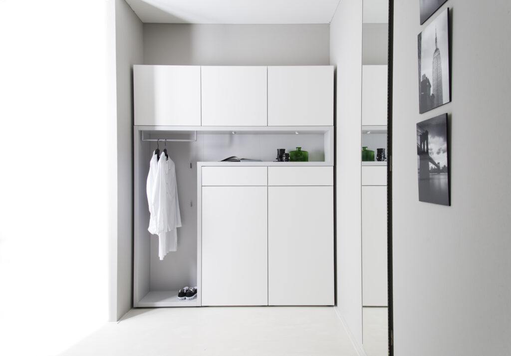 Zeitgemäßer Kleiderschrank in Weiß mit offenen Hängeelementen, geschlossenen Türen und Spiegel – aufgeräumtes Design mit klarer Struktur
