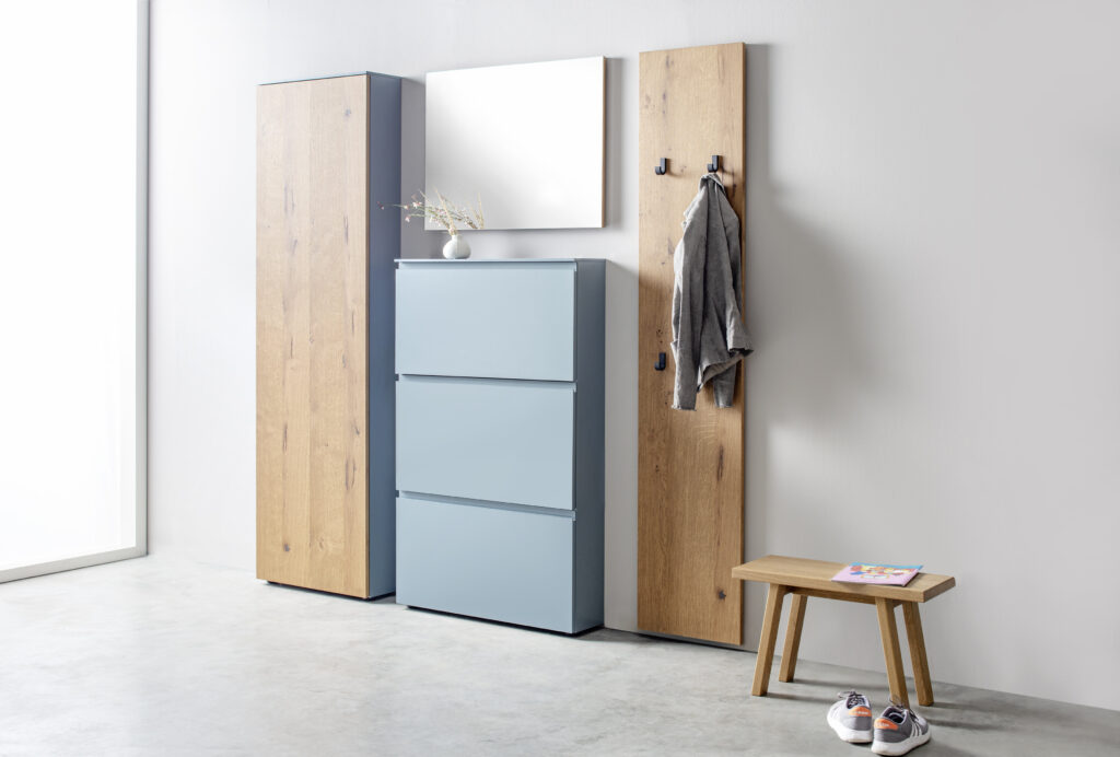 Moderner Eingangsbereich mit hohem Holzschrank, hellblauem Schuhschrank, Wandpaneel mit Haken und Bank – funktionale Gestaltung mit klarer Linienführung