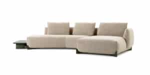 Modernes, beiges Ecksofa mit drei großen Rückenpolstern, rechter Chaiselongue und integriertem, niedrigem Beistelltisch aus dunklem Holz – minimalistisches Design mit kontrastreichen Materialien.