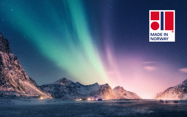 Beeindruckende Aurora Borealis über verschneiten Bergen in Norwegen; grüne und violette Lichter tanzen über einer friedlichen, beleuchteten Landschaft.