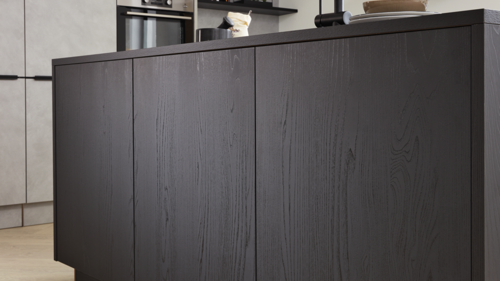 Moderne Küche mit dunkler Holzfront, darauf Geschirr und Küchenaccessoires wie Schalen und ein schwarzer Wasserhahn. Im Hintergrund helle Schränke und ein Regal mit Vorräten