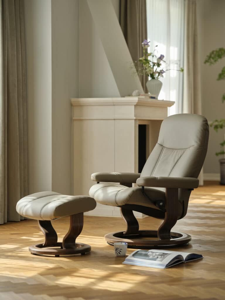 Beiger Stressless Consul Relaxsessel mit Hocker neben einem Kamin.