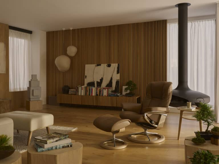 Brauner Stressless Relaxsessel mit Hocker in einem modernen Wohnzimmer mit Holzdetails und Kamin.