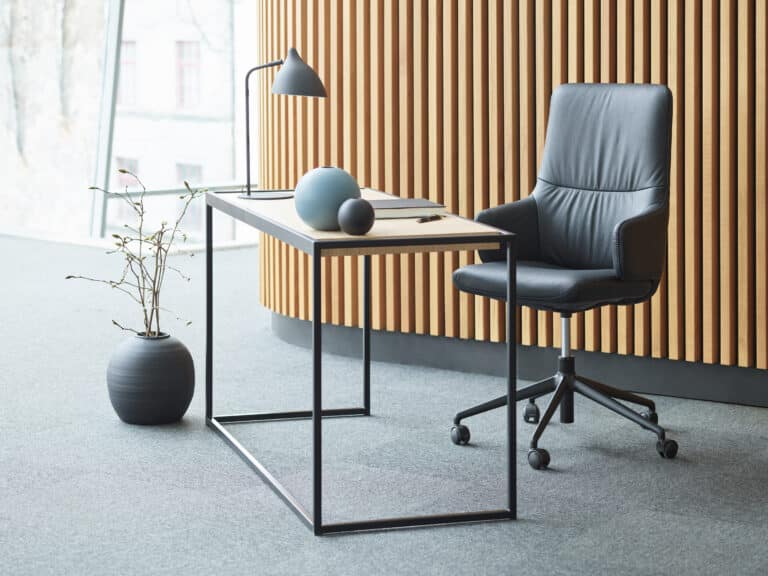 Schwarzer Stressless Mint Home-Office-Stuhl mit Armlehnen an einem modernen Schreibtisch.